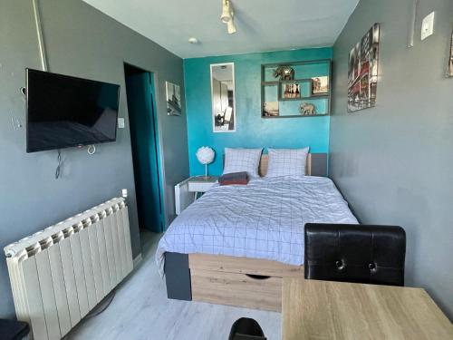um quarto com uma cama e uma televisão de ecrã plano em Studio cosy indépendant avec Jardin à Osny proche Cergy Pontoise em Osny