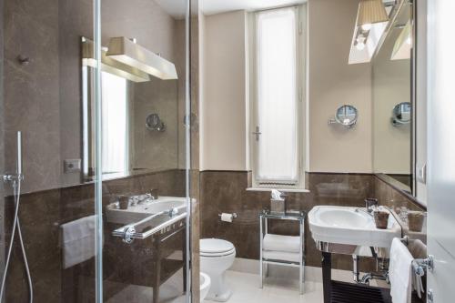 a bathroom with two sinks and a toilet and a shower at Hotel Francia E Quirinale in Montecatini Terme