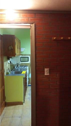 cocina con fregadero y pared de ladrillo en Marta en Villa Gesell