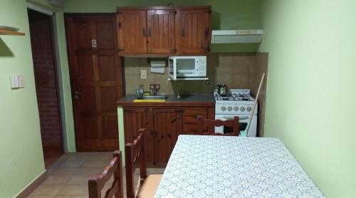 uma cozinha com armários de madeira, uma mesa e um fogão em Marta em Villa Gesell