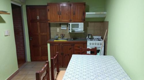 cocina con armarios empotrados, mesa y fogones en Marta en Villa Gesell