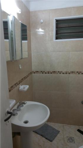 uma casa de banho com um lavatório branco e um espelho. em Marta em Villa Gesell