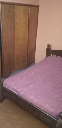 um quarto com uma cama roxa e um armário de madeira em Marta em Villa Gesell