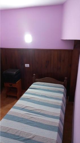 uma cama num quarto com uma parede roxa em Marta em Villa Gesell