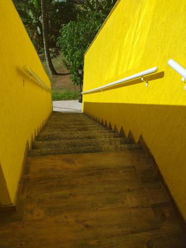 a stairway with a yellow wall and a wooden floor at Hospedagem Encantos da Serra in Itatiaia