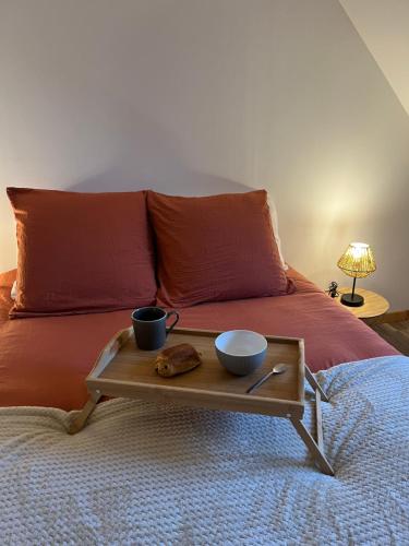 a bed with two cups and a tray on it at La maison l escalier des falaises in Sotteville-sur-Mer