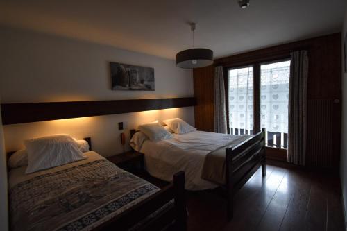 - une chambre avec 2 lits et une fenêtre dans l'établissement Hôtel Le Chinfrey, aux Gets
