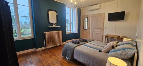 a bedroom with a large bed and a television at Chambres et Gîtes Les Deux Chênes près de Bergerac in Le Fleix