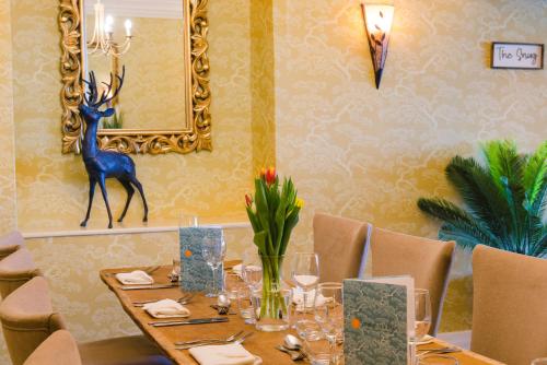 a dining room with a table with a deer statue on the wall at Cricklade House Hotel, Sure Hotel Collection by Best Western in Cricklade