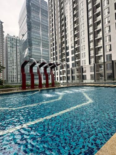 een groot zwembad met blauw water voor hoge gebouwen bij SENTRAL SUITES in Kuala Lumpur