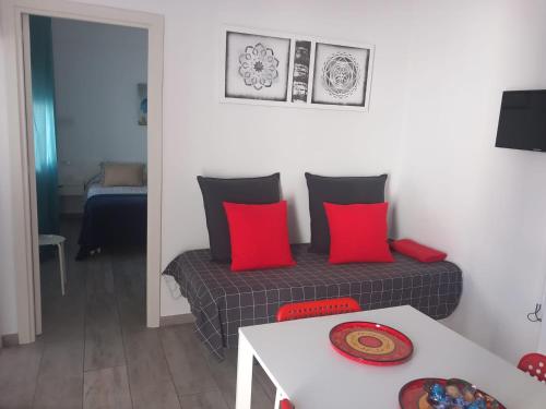 ベヘール・デ・ラ・フロンテーラにあるCasa Patio Paraísoのリビングルーム(赤い枕とテーブル付きのベッド付)