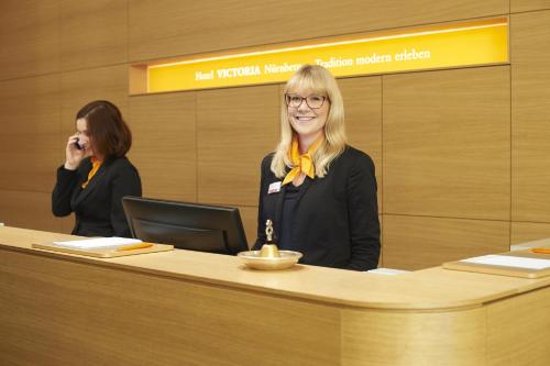 a woman is sitting at a reception desk at Hotel VICTORIA Nürnberg in Nürnberg