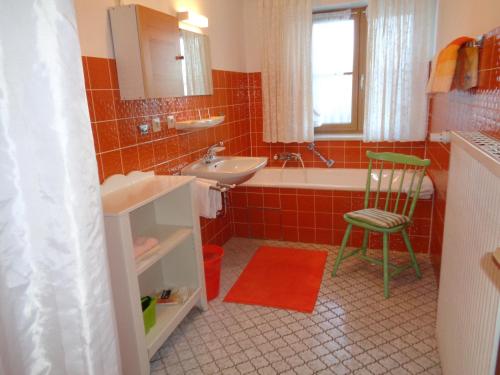 een badkamer met een bad, een wastafel en een stoel bij Ferienwohnungen Lackner - Chiemgau Karte in Inzell