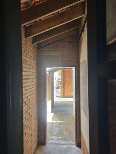 um corredor vazio com uma parede de tijolos e uma porta aberta em GEBA1265 em Guaratinguetá