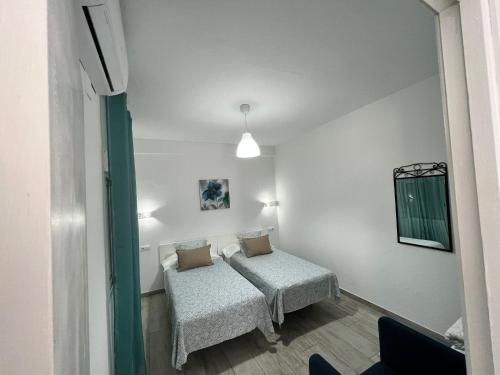 ベヘール・デ・ラ・フロンテーラにあるCasa Patio Paraísoの小さな部屋で、ベッド2台、鏡が備わります。