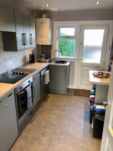 una cocina con electrodomésticos de acero inoxidable y una ventana en Springbank Holiday Home en Dunfermline