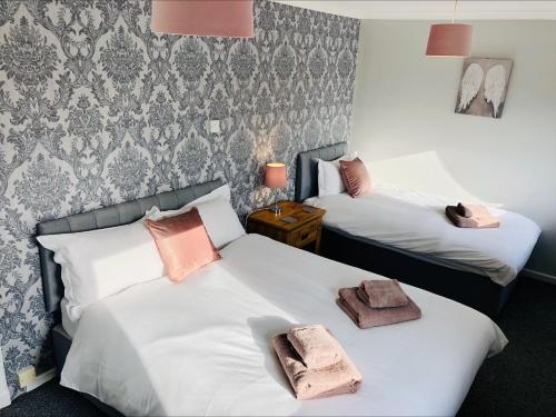 two beds in a hotel room with towels on them at Springbank Holiday Home in Dunfermline