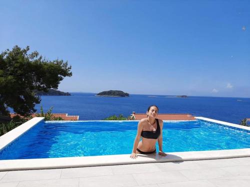una mujer en bikini sentada junto a una piscina en Mediterranean Jewel, en Blato