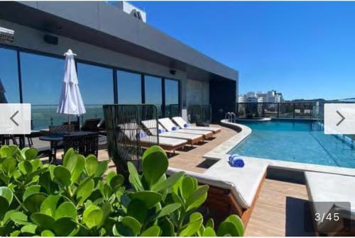 a pool on top of a building with chairs and an umbrella at Hotel Boutique Brava Mundo - SC in Itajaí