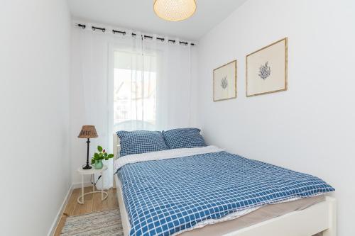 a bedroom with a bed with blue sheets and a window at Apartament Turkus z basenem in Sztutowo