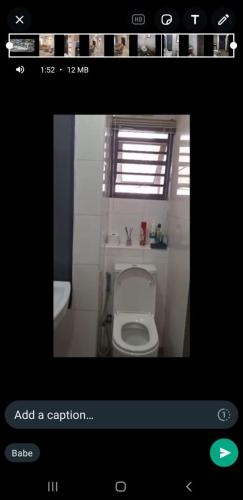 a bathroom with a white toilet and a window at Mengary Apartment in Suru Lere