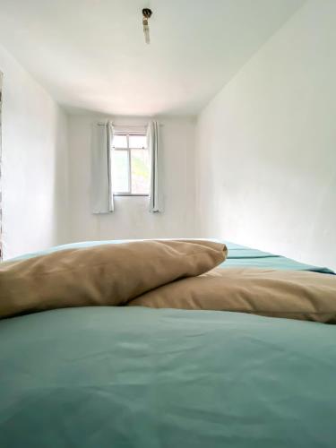 Ce lit se trouve dans un dortoir blanc doté d'une fenêtre. dans l'établissement Quarto Privativo no Vidigal, à Rio de Janeiro