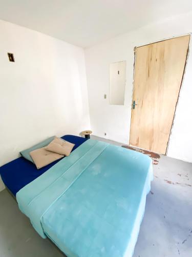 Cette chambre dispose d'un lit bleu avec une porte. dans l'établissement Quarto Privativo no Vidigal, à Rio de Janeiro