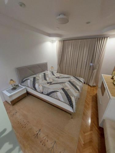 a bedroom with a large bed and a night stand at Matej LUX Apartment in Skopje