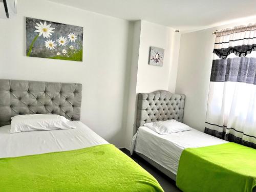 two beds in a bedroom with green sheets at Apartamento Comodo, Cerca al Rio Guatapuri in Valledupar