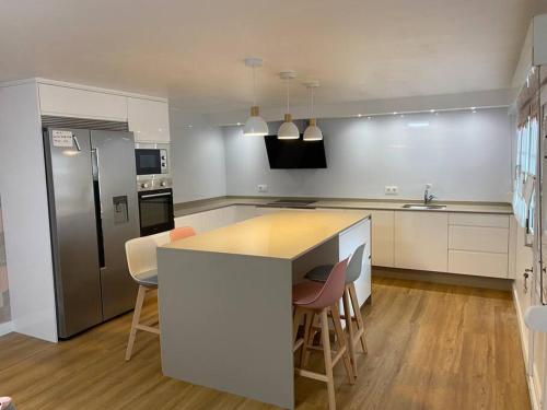 a kitchen with a counter with chairs and a refrigerator at Casa en Playa Las Sinas in Villanueva de Arosa