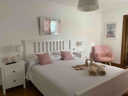 a bedroom with a large white bed with shoes on it at Casa en Playa Las Sinas in Villanueva de Arosa