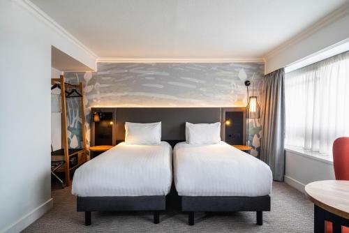 a hotel room with two beds and a table at Mercure Bedford Centre Hotel in Bedford