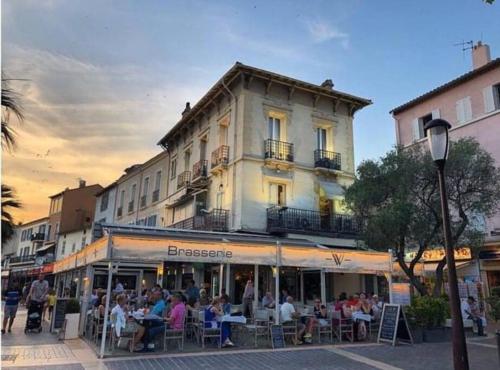 a group of people sitting at tables in front of a building at Proche mer Appart 2 pièce Wifi&Clim in Sainte-Maxime