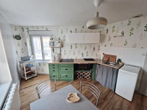 une cuisine avec des placards verts et une table avec des chaises dans l'établissement Joli appartement rénové (Hirondelle), à Cornimont
