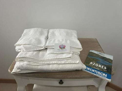 een stapel handdoeken op een tafel met een boek bij Villarelva in Ponta Delgada
