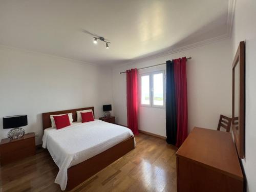 a bedroom with a bed and a window with red curtains at Villarelva in Ponta Delgada