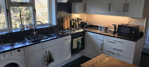 a kitchen with white cabinets and a sink and a stove at Spacious Rooms close to Aylesbury Centre - Free Fast WiFi in Buckinghamshire