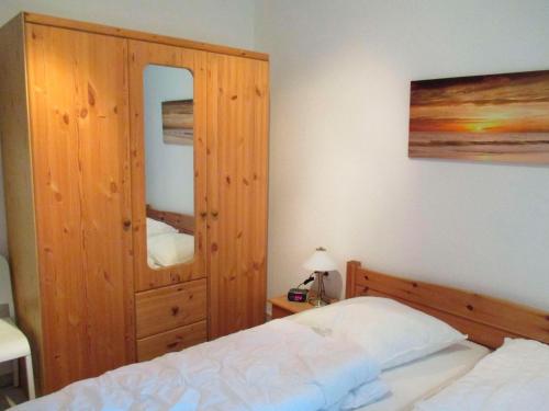 ヴァンガーラントにあるFerienwohnung Zum alten Friesen BODOのベッドルーム1室(ベッド1台付)、大きな木製キャビネットが備わります。