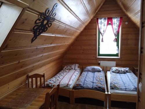 two beds in a log cabin with a window at Apartamenty Pokoje Zakopane in Zakopane