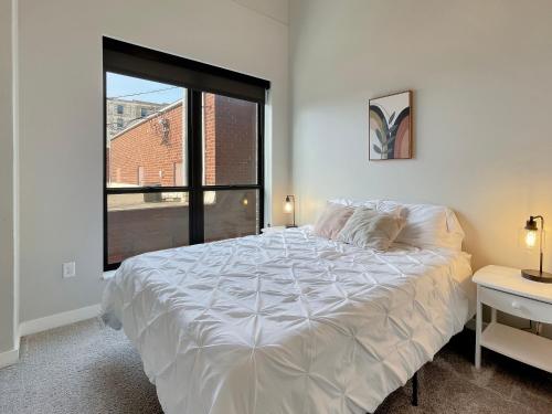 a white bed in a room with a large window at 2br Skyline Apt With Panoramic Views Downtown in Des Moines