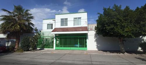 a white building with a green gate in front of it at Habitación mamá coco in Aguascalientes