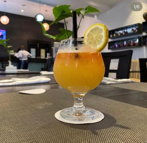 a glass of orange juice with a lemon on a table at Golden Tulip Oniru Suites in Lagos