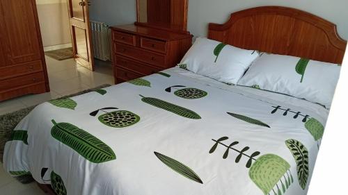 - un lit avec une couette blanche et des feuilles vertes dans l'établissement A parada da Ribeira, à Ourense