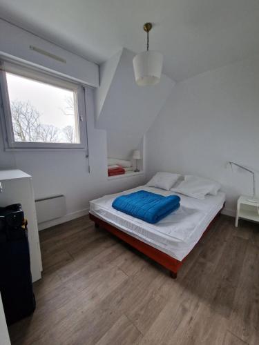 - une chambre blanche avec un lit et une couverture bleue dans l'établissement Appartement charmant bord de mer, à Cabourg
