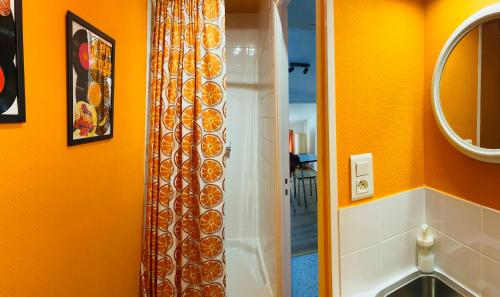 - un rideau de douche dans la salle de bains aux murs orange dans l'établissement Spacieux Studio Seventies: voyage dans le temps, à Gannat