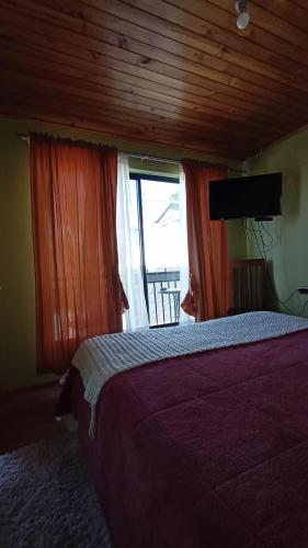 a bedroom with a bed and a large window at Lucerna Hostería in Curanipe