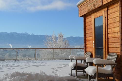 a group of chairs sitting on a porch in the snow at Jägerhotel in Annenheim