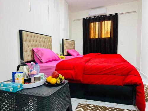 ein Schlafzimmer mit einem roten Bett und einem Tisch mit Obst darauf in der Unterkunft Villa Fayrouz pyramids Inn in Kairo