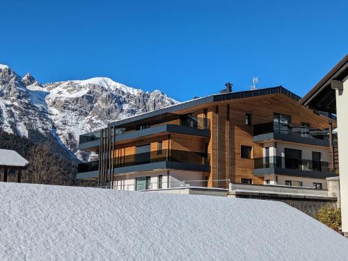 a building with snowy mountains in the background at Chalet Larix Andalo Deluxe Apartments in Andalo