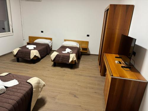 a room with two beds and a flat screen tv at Hotel La Torre in Formigine